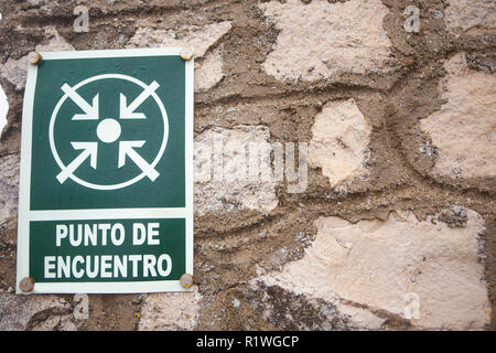Punto di incontro segno attaccato al muro di pietra. Spanish languaje lettera Foto Stock
