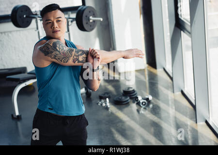 Giovani asiatici sportivo facendo stretching esercizio in palestra Foto Stock