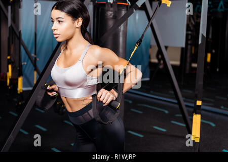 Bella ragazza sportive esercitano con cinghie di sospensione in sport palestra Foto Stock