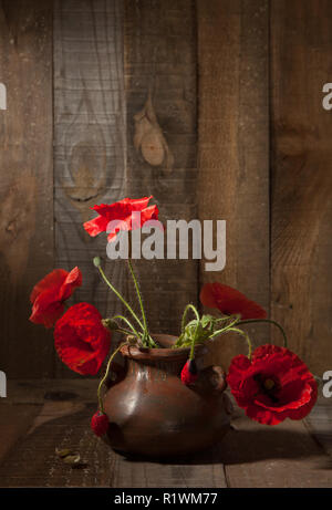 Poppies in pentola di creta contro le vecchie pareti in legno Foto Stock