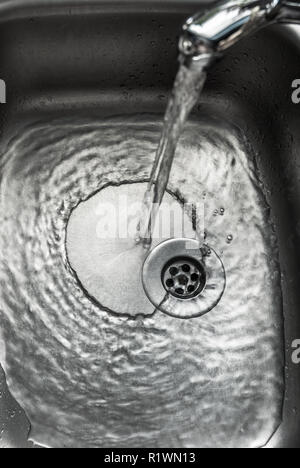 Chrome lavello con acqua di versamento. Foto Stock