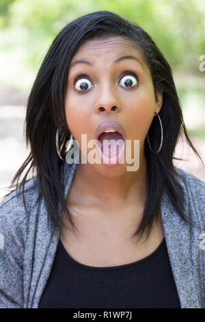 ritratto di una giovane donna con le mani sul viso eccitato su sfondo bianco Foto Stock