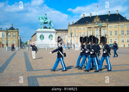 Danish Royal Guard marciando in piazza con il Palazzo di Amalienborg e Frederic monumento Foto Stock