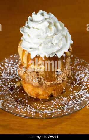 Dessert stratificato costituito da una torta di mele e rabboccato con caramello salato gelato e un ciuffo di panna montata Foto Stock