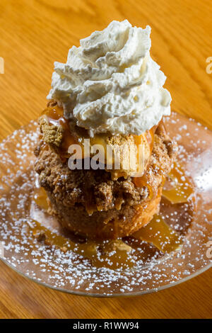 Dessert stratificato costituito da una torta di mele e rabboccato con caramello salato gelato e un ciuffo di panna montata Foto Stock