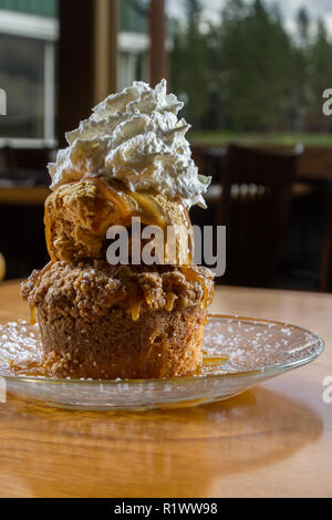 Dessert stratificato costituito da una torta di mele e rabboccato con caramello salato gelato e un ciuffo di panna montata Foto Stock