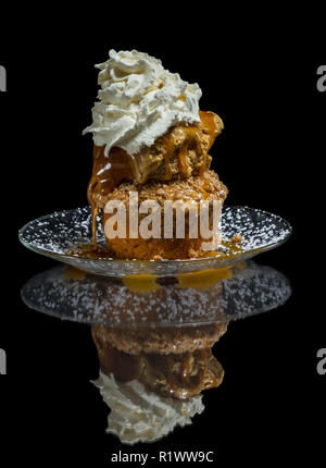 Dessert stratificato costituito da una torta di mele e rabboccato con caramello salato gelato e un ciuffo di panna montata Foto Stock