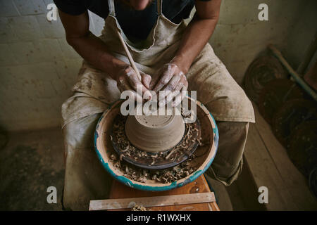 Immagine ritagliata di professional potter decorazione di pentola di creta in officina Foto Stock