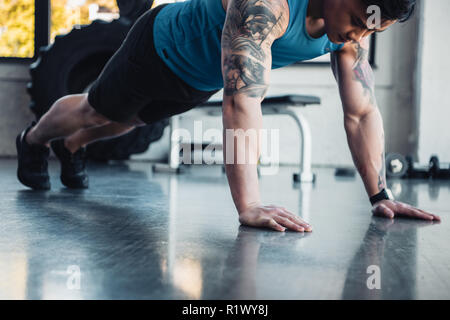 Vista ritagliata della giovane atleta listone facendo esercizio in palestra Foto Stock