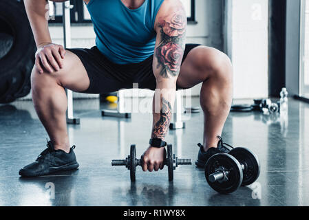 Vista parziale del giovane atleta esercizio con manubri in palestra Foto Stock