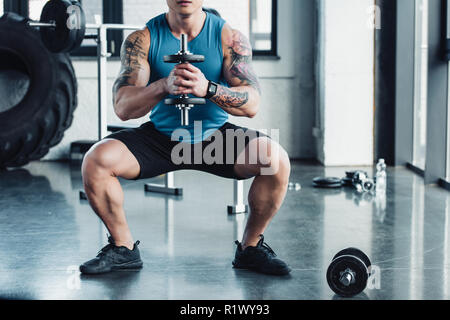 Vista parziale del giovane sportivo che esercitano con il manubrio in palestra Foto Stock