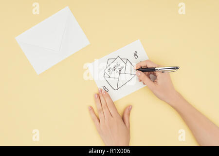 Persona tagliate la scrittura di carta bianca con la ringrazio scritte fuori di mano disegnato involucro isolato su sfondo giallo Foto Stock