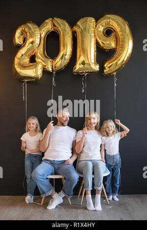 La famiglia felice Holding firmano 2019 fatta di golden palloncini per nuovo anno su sfondo nero. Foto Stock