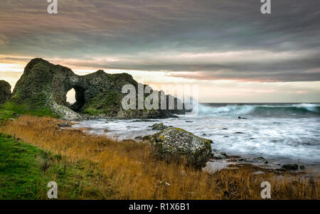 Questa è una foto di uno degli archi del mare a Ballintoy sulla costa di Antrim in Irlanda del Nord. Questa è stata scattata appena prima il sole è andato giù Foto Stock