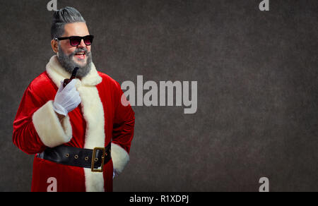 Babbo Natale con un'acconciatura e un sigaro lancia un fumo allegro Foto Stock