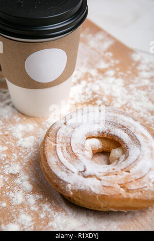 Tazza di caffè caldo con choux torta sul tavolo di legno su sfondo bianco. Colazione veloce. Cucina francese. Buona mattina. Foto Stock