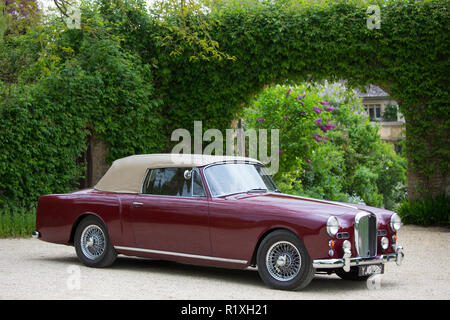 British realizzato Alvis TD21 serie DHC 1 drophead coupe auto classica in Peonia colore con il cofano fino parcheggiato nel Cotswolds, Inghilterra Foto Stock