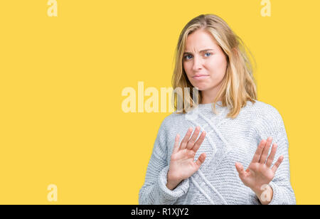 Giovane e bella donna che indossa un maglione invernale su sfondo isolato disgustato espressione, orinato e timorosi facendo il disgusto di fronte perché avversione Foto Stock