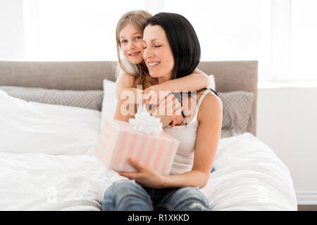 Felice Festa della mamma. Un bambino figlia si congratula con le mamme e dà il suo dono Foto Stock
