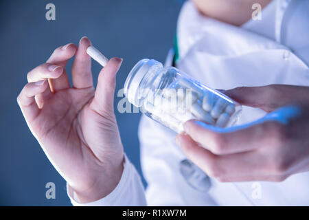 Womans mano trattiene pillola bianca tirata fuori dal vaso. Visualizzazione orizzontale Foto Stock