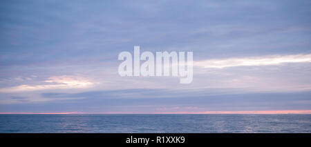 Mozzafiato, spettacolari colori pastello del tramonto sopra il mare calmo dell'Oceano Atlantico in Galles Foto Stock