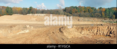 Un grande colline e cave di sabbia e tracce di un bulldozer pesanti e trattori su una foresta di autunno sito in costruzione. Collage panoramico da diversi fuori Foto Stock