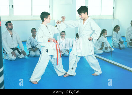 Coppia di ragazzi combattimenti in combattimento per utilizzare nuove mosse alla classe di karate Foto Stock