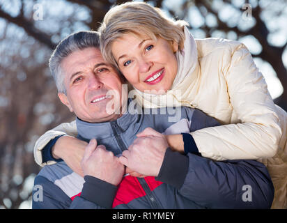 Positivo il marito e la moglie che abbraccia calorosamente e il riposo insieme all'aperto Foto Stock