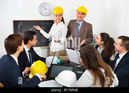 Professionisti positivo con i laptop e caschi con riunione di lavoro Foto Stock