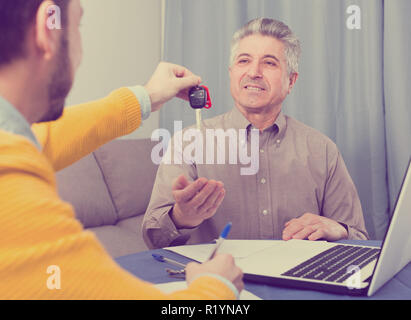 Uomo maturo e manager firmato il contratto leasing auto a casa e consegnare le chiavi Foto Stock