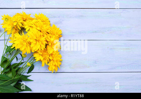 Un mazzo di fiori di giallo Heliopsis fiori su un blu sullo sfondo di legno. Foto Stock