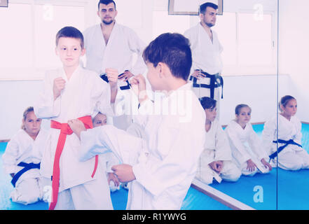 Due giovani ragazzi della formazione in combattimento per utilizzare una nuova tecnica di classe di karate Foto Stock