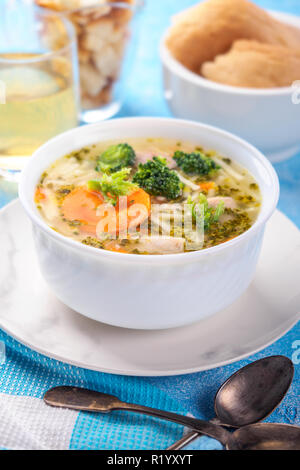 Italiano minestra di verdura con i broccoli carote tagliatelle in brodo di pollo sul tavolo blu con fette di pane e il succo di vetro. Cibo vegetariano ancora organico vita in stile luce close-up Foto Stock