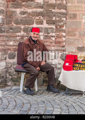 Istanbul, Turchia, Novembre 13, 2012: Turco uomo vendita cappelli turchi al di fuori del Museo Chora di Balat. Foto Stock