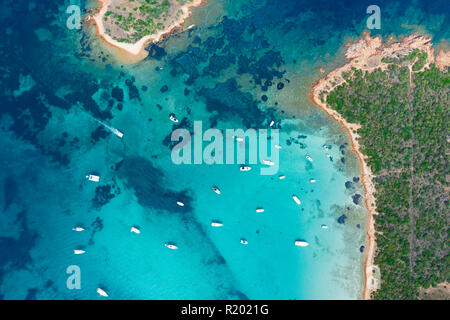 Spettacolare vista aerea di alcune barche e piccole imbarcazioni galleggianti su una chiara e il mare turchese, Sardegna, Italia. Foto Stock