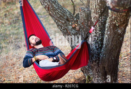 L uomo per rilassarsi in un'amaca su un viaggio escursionistico Foto Stock