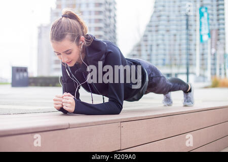 Montare youn donna facendo esercizio tavoloni outdoor in ambiente urbano Foto Stock