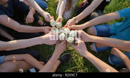 Nove amici clink bicchieri di gelato. Le mani di close-up. Foto Stock