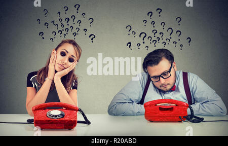 Triste l uomo e la donna in attesa di una chiamata di telefono da ogni altra hanno molte domande Foto Stock