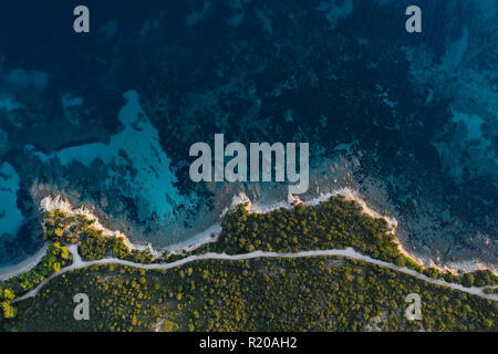 Vista aerea di un sorprendente e rocciosa costa verde bagnata da un trasparente e mare turchese. Sardegna, Italia. Foto Stock