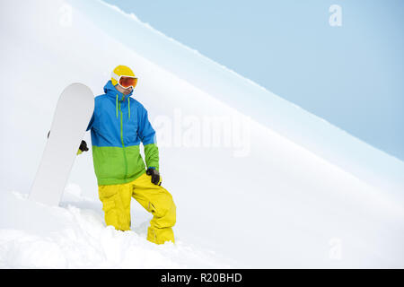 Snowboarder sorge sul pendio backcountry e trattiene lo snowboard. Concetto di sci Foto Stock