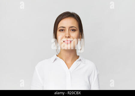 Felice bruna giovane donna che indossa una camicia bianca sorridente ritratto contro uno sfondo bianco Foto Stock