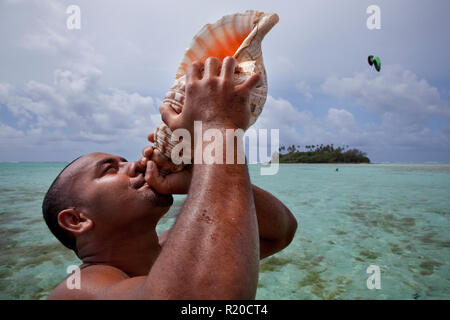 Guida locale di suonare su una conch horn in muri Lagoon, Rarotonga Isole Cook. Foto Stock