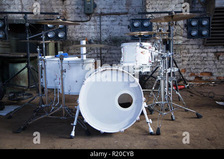 White drum set industriale in camera bianca su sfondo mattone. Foto Stock