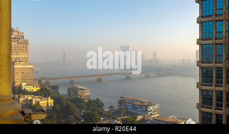 Il Cairo in Smog: smoggy vista della università del Cairo Bridge da Giza al Cairo sul Fiume Nilo, grattacieli, Hyatt Grand Nile Tower ristorante girevole Foto Stock