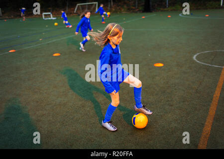 Ragazza pratica soccer drill sul campo di notte Foto Stock