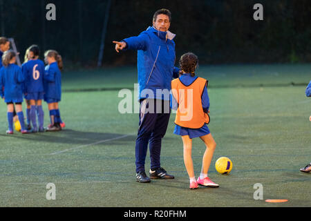 Allenatore di calcio ragazza guida i giocatori di calcio la pratica sul campo di notte Foto Stock