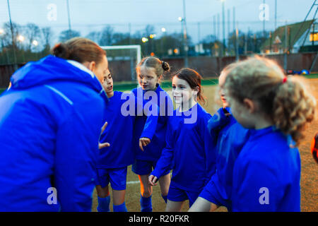 Ragazze Calcio team ascolto di pulmann in huddle Foto Stock