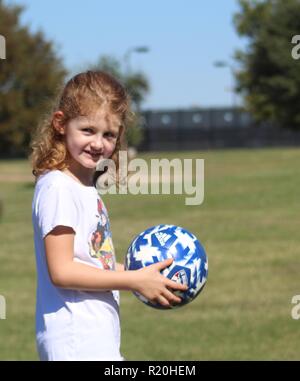 6 anno vecchio redheaded ragazza con pallone da calcio Foto Stock