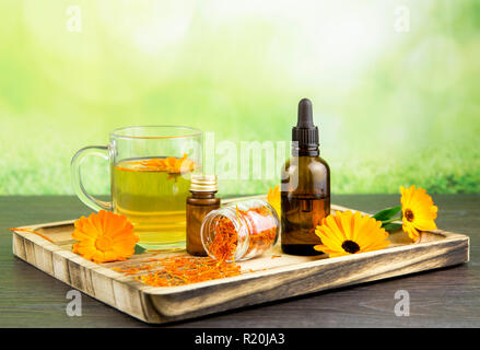 Calendula officinalis, la calendula, sinopie, comune calendula o Scotch calendula diversi prodotti di salute sul vassoio in legno, olio essenziale, tintura Foto Stock